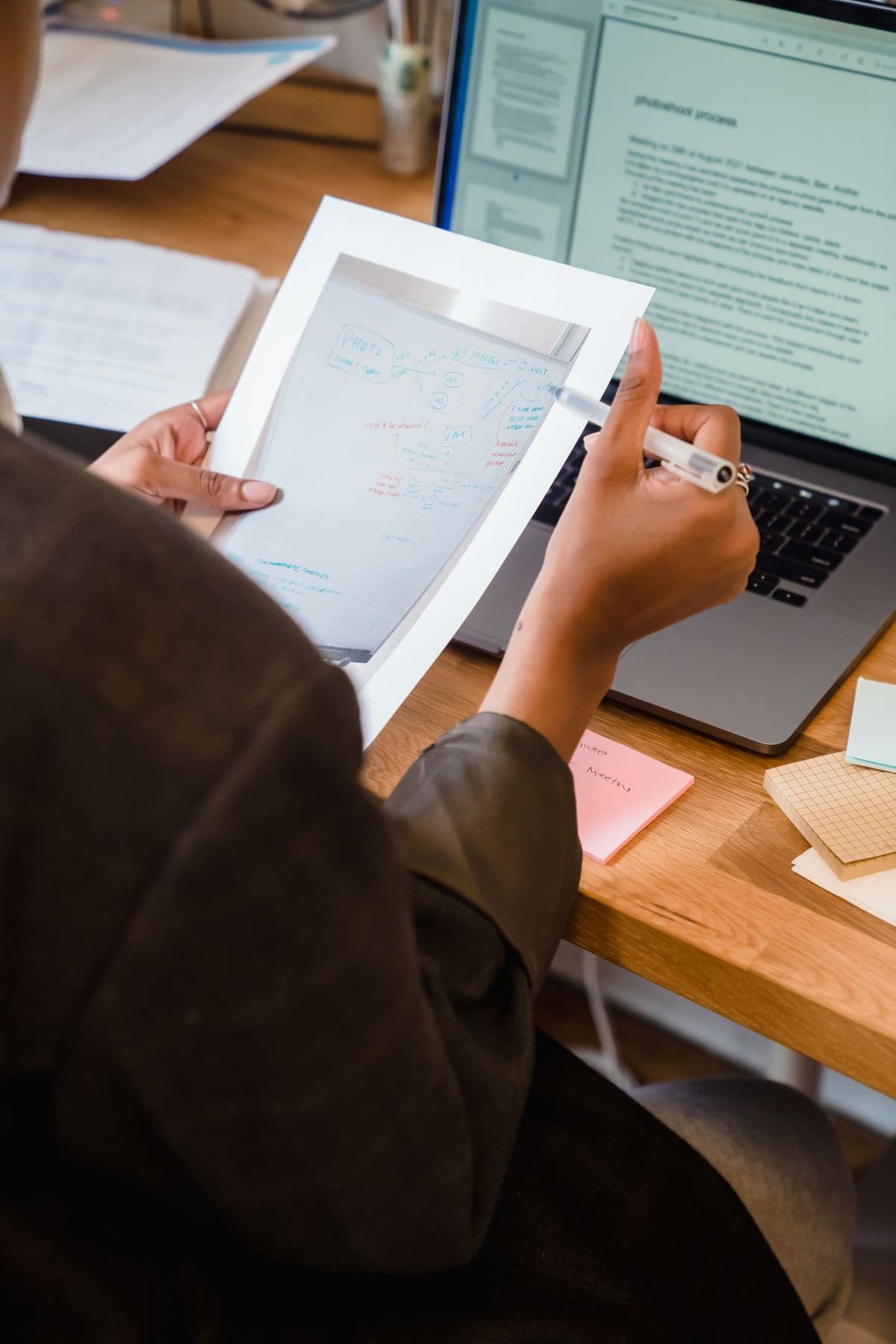 A professional reviewing an annotated page beside an open laptop — illustrative stock photo